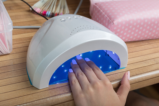 drying nail polish, gel nails, Woman using UV light dryer