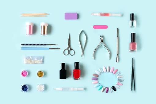 Set of various manicure and pedicure tools and accessories on light blue background. Top view.