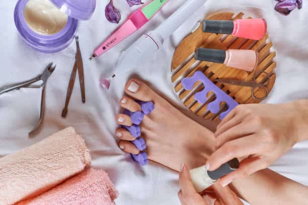 Applying pedicure to woman's feet, with the nail kit with toe separator and tools kit