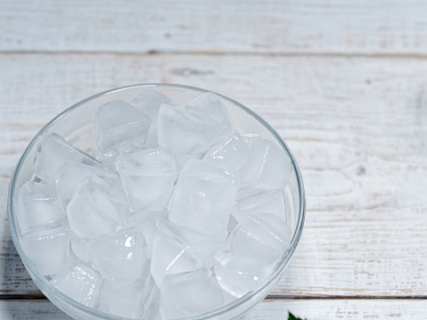 Ice cubes in a bowl on the white wooden table, dry regular nail polish quick and fast with ice water
