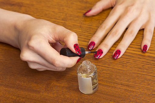 Women's hands ,make the topcoat to the nails. dry nail polish fastly using top coat