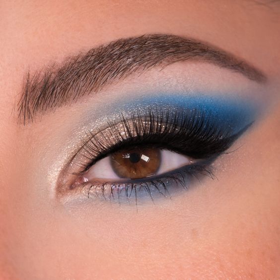 light glittery golden eyeshadow with blue shade on eye corner with long thick eyeliner blue eyeshadow makeup