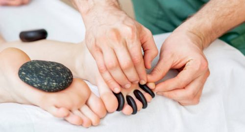hot stone pedicure massage on toes by a pedicurist