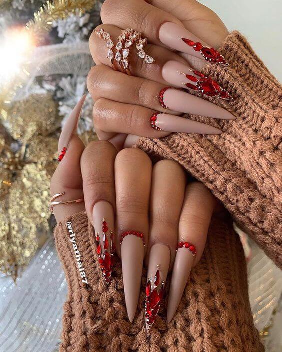 very long nude pointy nails with red stones design